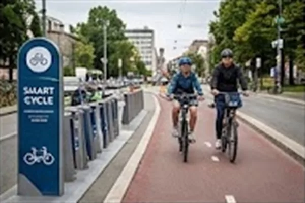 Vélos en libre-service et signalétique urbaine Station de vélos en libre-service avec signalétique urbaine et cyclistes sur piste cyclable
